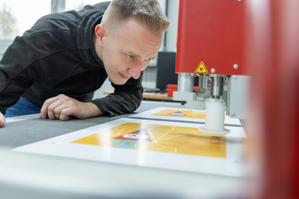 Mitarbeiter der gebeugt über den sich in der Entwicklung befindenden Druckvorlagen ist.