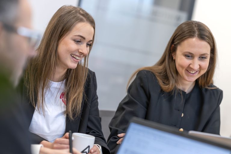 Zwei lachende Frauen die in einer Besprechung zur Markenentwicklung sitzen.