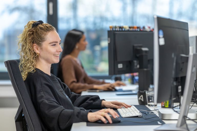 Lächelnde Mitarbeiterin an Ihrem Arbeitsplatz im MEDIAHAUS -Reproduktion