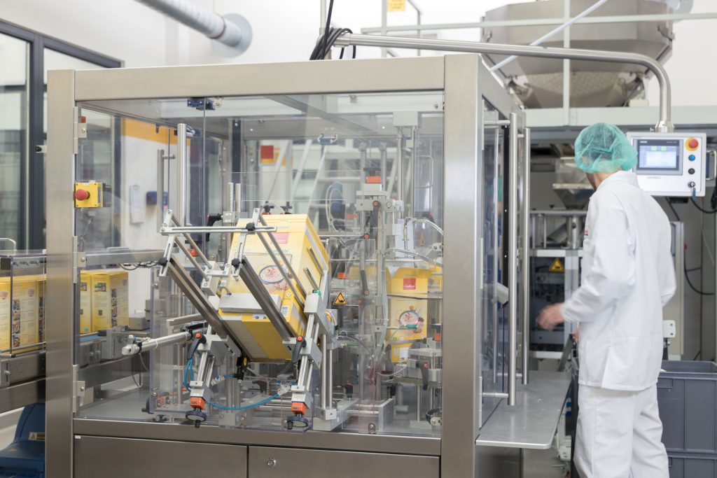 Mitarbeiter aus der Druckerei in Schutzkleidung an der Druckmaschine.